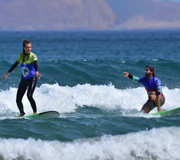 Instructor de surf da indicaciones a su alumna en el agua
